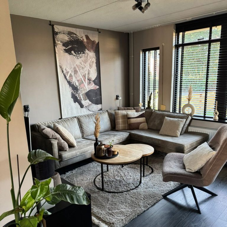 Woonkamer interieurstylist Een moderne woonkamer met een grote bank, een ronde tafel en kunst aan de muur.