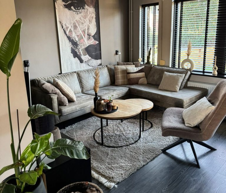 Woonkamer interieurstylist Een moderne woonkamer met een grote bank, een ronde tafel en kunst aan de muur.